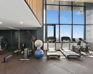 a gym with cardio equipment in a large room with windows at Central Comfort CBD 2BR Apartment with Pool and Gym SKT1002 in Brisbane