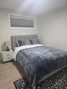 a bedroom with a bed with a blue comforter at Cozy & Stylish 1BR Suite in Regina