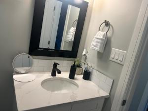 a bathroom with a white sink and a mirror at Cozy Family Friendly Suite Near Whyte, UofA, Kinsmen with Desks or Home-office and Full Kitchen in Edmonton +26 photos
