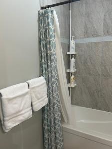a bathroom with a shower curtain next to a tub at Cozy Family Friendly Suite Near Whyte, UofA, Kinsmen with Desks or Home-office and Full Kitchen in Edmonton