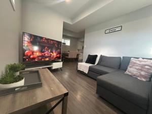 a living room with a couch and a flat screen tv at Cozy Family Friendly Suite Near Whyte, UofA, Kinsmen with Desks or Home-office and Full Kitchen in Edmonton