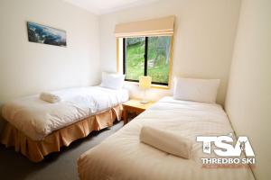 two beds in a room with a window at Mowamba E6 in Thredbo