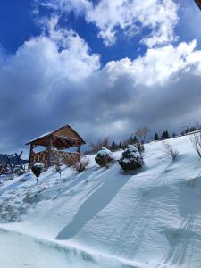 a snow covered field with a wooden gazebo at Сільська садиба in Yablunytsya