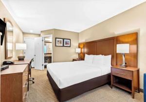 Una habitación de hotel con una cama grande y un escritorio. en Aurora Inn, en Modesto