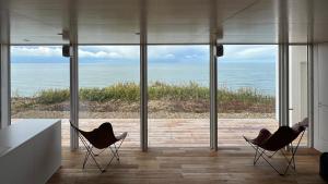 2 stoelen in een kamer met uitzicht op de oceaan bij Cliff House MORAI 2 