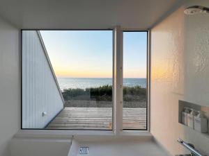een badkamer met een raam met uitzicht op de oceaan bij Cliff House MORAI 2 