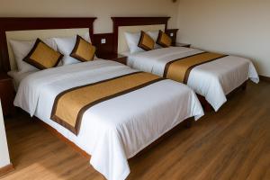 two beds in a hotel room with white sheets at Hồng Trà Hotel Quảng Ninh in Quang Ninh