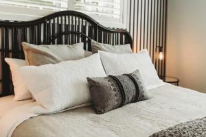 a bed with white and gray pillows on it at Buller Noire - luxury New Plymouth oceanview home in New Plymouth