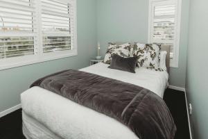 a bedroom with a large bed with two windows at Buller Noire - luxury New Plymouth oceanview home in New Plymouth +18 photos