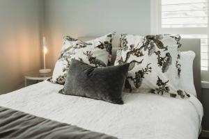a bed with white sheets and pillows on it at Buller Noire - luxury New Plymouth oceanview home in New Plymouth