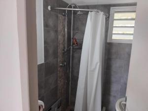 a shower with a white shower curtain in a bathroom at Maison charmante à Rivière-Pilote avec vue sur la montagne in Rivière-Pilote