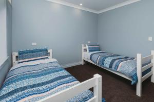 deux lits dans une chambre aux murs bleus dans l'établissement Weld Cottage - Sustainable lifestyle property, à New Plymouth