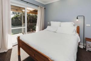 une chambre avec un lit avec des draps blancs et une fenêtre dans l'établissement Weld Cottage - Sustainable lifestyle property, à New Plymouth