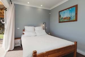 - une chambre dotée d'un lit avec des draps blancs et un tableau dans l'établissement Weld Cottage - Sustainable lifestyle property, à New Plymouth 20 autres photos