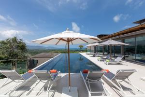 a pool with chairs and an umbrella next to a pool at Tropical Castle Villa in Phuket