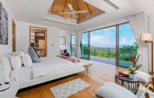 a bedroom with a white bed and a large window at Tropical Castle Villa in Phuket