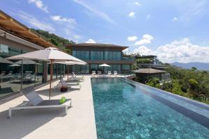 a pool with chairs and umbrellas next to a building at Tropical Castle Villa in Phuket