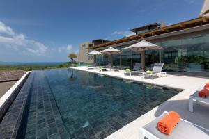 a swimming pool with chairs and umbrellas next to a building at Tropical Castle Villa in Phuket +16 photos