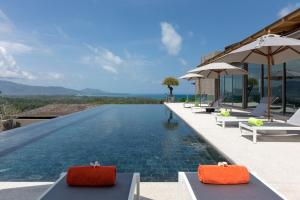 an infinity pool at a resort with chairs and umbrellas at Tropical Castle Villa in Phuket
