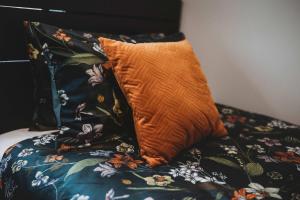 an orange pillow sitting on top of a bed at Bell Block Beauty - pristine 3BR home near beach in New Plymouth