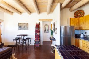 La cuisine est équipée d'un réfrigérateur et de tabourets de bar. dans l'établissement Casa de Alfarero - Hot Tub - EV Charger - Gas Grill - Mountain Views, à Arroyo Hondo