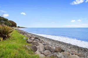 a rocky beach with the ocean in the background at Beachfront Breeze - sea views for days in New Plymouth