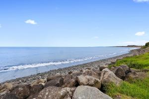 a rocky beach with the ocean in the background at Beachfront Breeze - sea views for days in New Plymouth