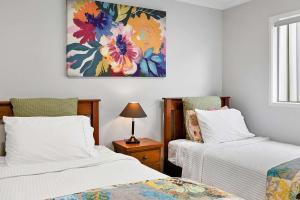a bedroom with two beds and a painting on the wall at Beachfront Breeze - sea views for days in New Plymouth +17 photos