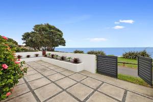 a patio with a white fence and flowers at Beachfront Breeze - sea views for days in New Plymouth