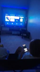 een persoon die op een bank zit en een mobiele telefoon vasthoudt bij Melody Homestay in Kuala Kedah