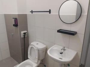 a bathroom with a toilet and a sink and a mirror at The Duta Loft in Bandar Puncak Alam