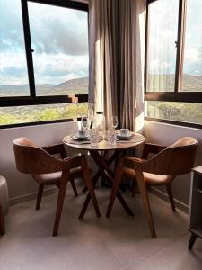 Apartamento luxo e novo com vista em Gravatá في غرافاتا: طاولة وكراسي في غرفة ذات نافذة كبيرة