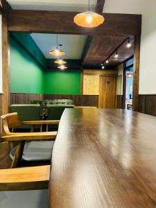 a conference room with a wooden table and green walls at Guest house Mitaki in Hiroshima