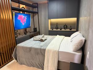 a bedroom with a large bed with a flat screen tv at DNA Flat Experiência, novo e lindo, com piscina incrível in Goiânia +12 photos
