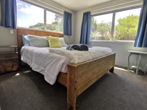 a bedroom with a large bed with blue curtains at Apartment style Beach House. Birdlings Flat in Little River