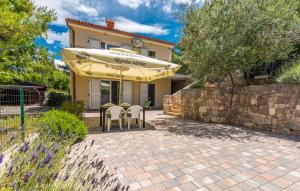 a patio with chairs and an umbrella in front of a house at Apartments in Soline - Insel Krk 41809 in Soline