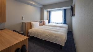 a small room with a bed and a window at Toyoko Inn Kochi in Kochi