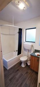 een badkamer met een bad, een toilet en een wastafel bij The Barnyard Cottage in Otakiri