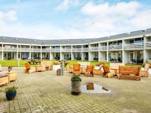 a large building with a patio with wooden benches at 4 person holiday home in Ringkøbing in Ringkøbing