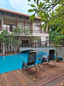 two chairs on a deck next to a swimming pool at The Castle Medan Penginapan Syariah in Medan