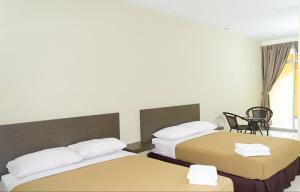 a hotel room with two beds and a chair at Hotel Darulaman Jitra in Jitra