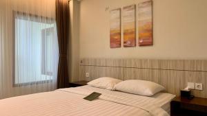 1 dormitorio con 1 cama con colcha blanca y ventana en The Baliem Hotel, en Jimbaran 58 fotos más