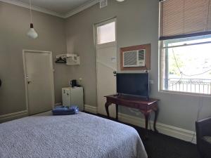 a bedroom with a bed and a desk and a television at Premier Hotel Collie in Collie