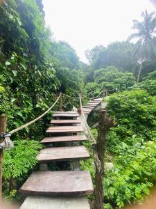 een houten brug in het midden van een bos bij Singing Frogs Jungle Stay in Ban Lamai