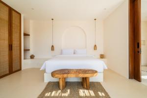 a bedroom with a white bed and a wooden table at Villa Cove 5 by BaliSuperHost in Uluwatu