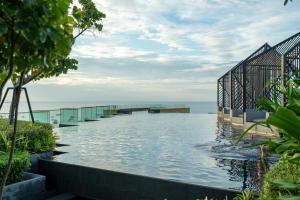 einen Infinity-Pool mit Meerblick im Hintergrund in der Unterkunft Edge Central Pattaya By Prop Hopper in Pattaya