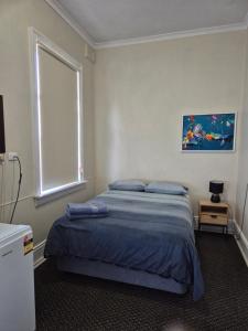 a bedroom with a bed with blue sheets and a window at Premier Hotel Collie in Collie