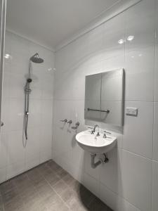 a white bathroom with a sink and a shower at Hillview Studio One in Berry