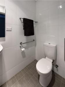a white bathroom with a toilet and a sink at Hillview Studio One in Berry