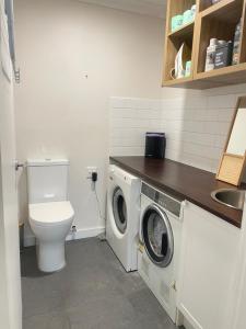 een badkamer met toilet en wasmachine en droger bij Cosy Guesthouse in Moss Vale +26 foto's
